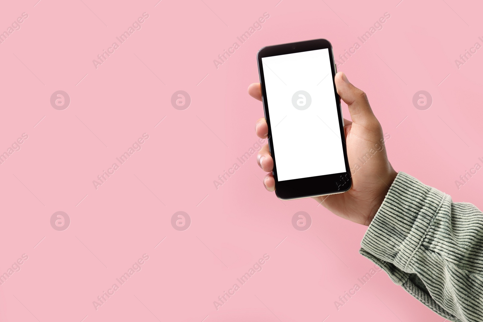 Photo of Man holding smartphone with blank screen on pink background, closeup. Mockup for design