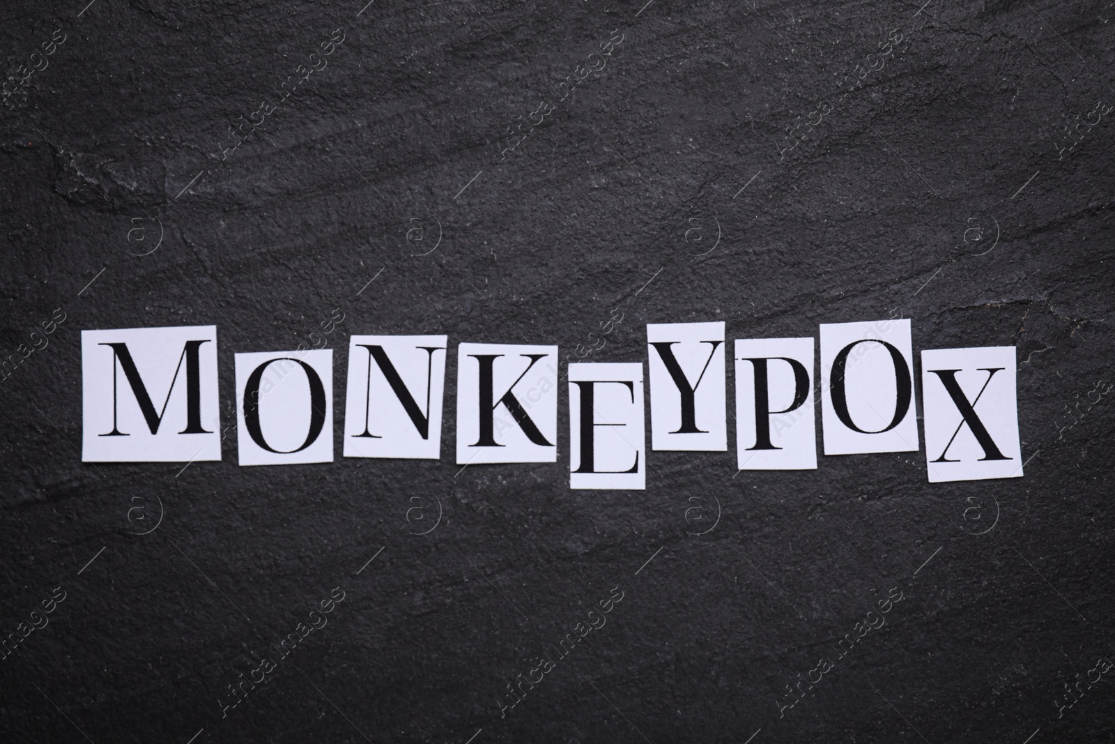 Photo of Word Monkeypox made of paper letters on black background, top view