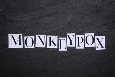 Photo of Word Monkeypox made of paper letters on black background, top view