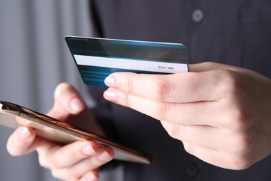 Online payment. Woman with smartphone and credit card indoors, closeup