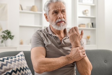 Arthritis symptoms. Man suffering from pain in wrist at home