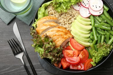 Photo of Healthy meal. Tasty products in bowl and cutlery on black wooden table, flat lay