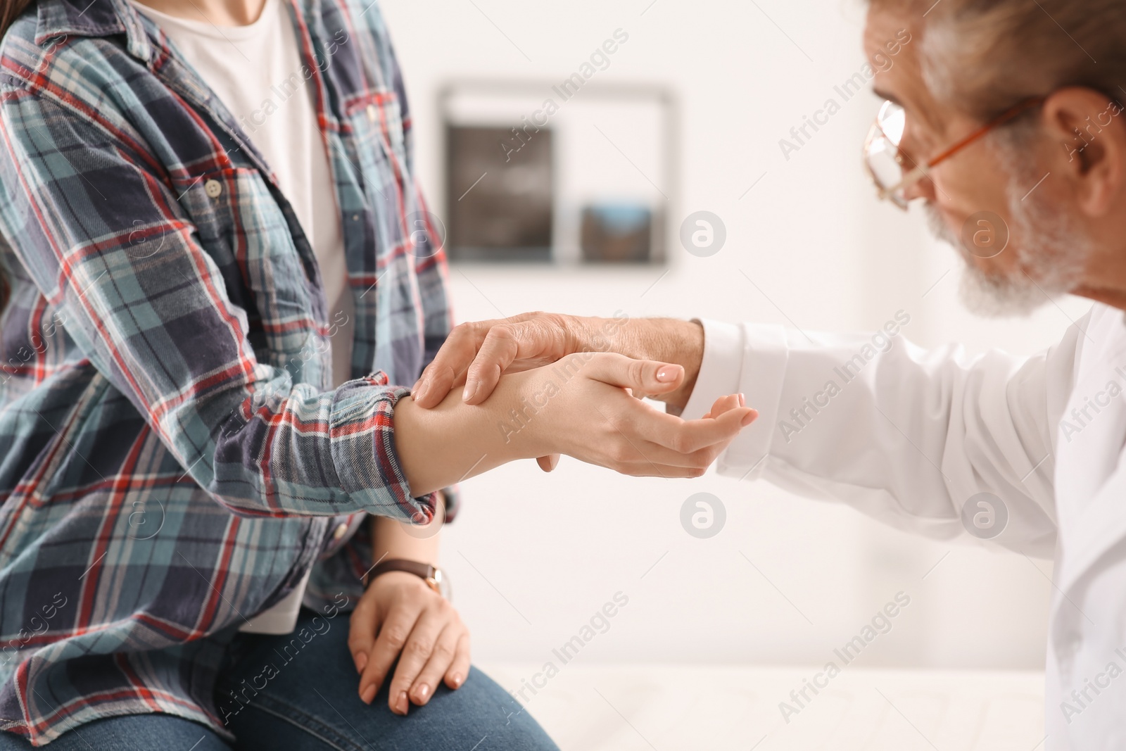 Photo of Orthopedist examining patient with injured hand in clinic, closeup