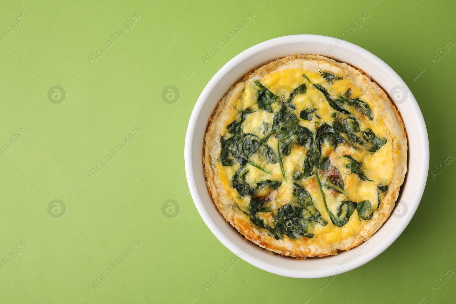 Photo of Delicious pie with spinach on green background, top view. Space for text