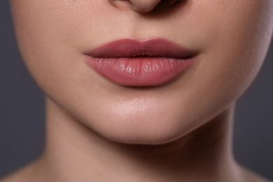 Photo of Woman with beautiful lips on grey background, closeup