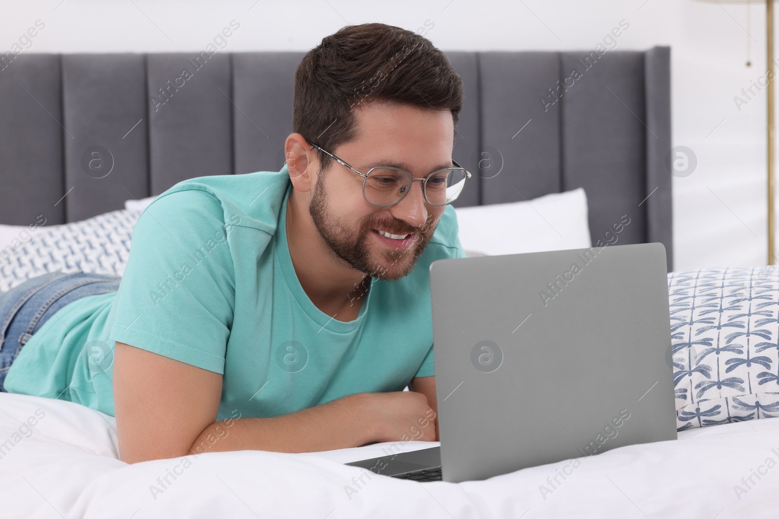 Photo of Happy man having video chat via laptop in bedroom