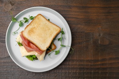 Photo of Tasty sandwich with brie cheese and prosciutto on wooden table, top view. Space for text
