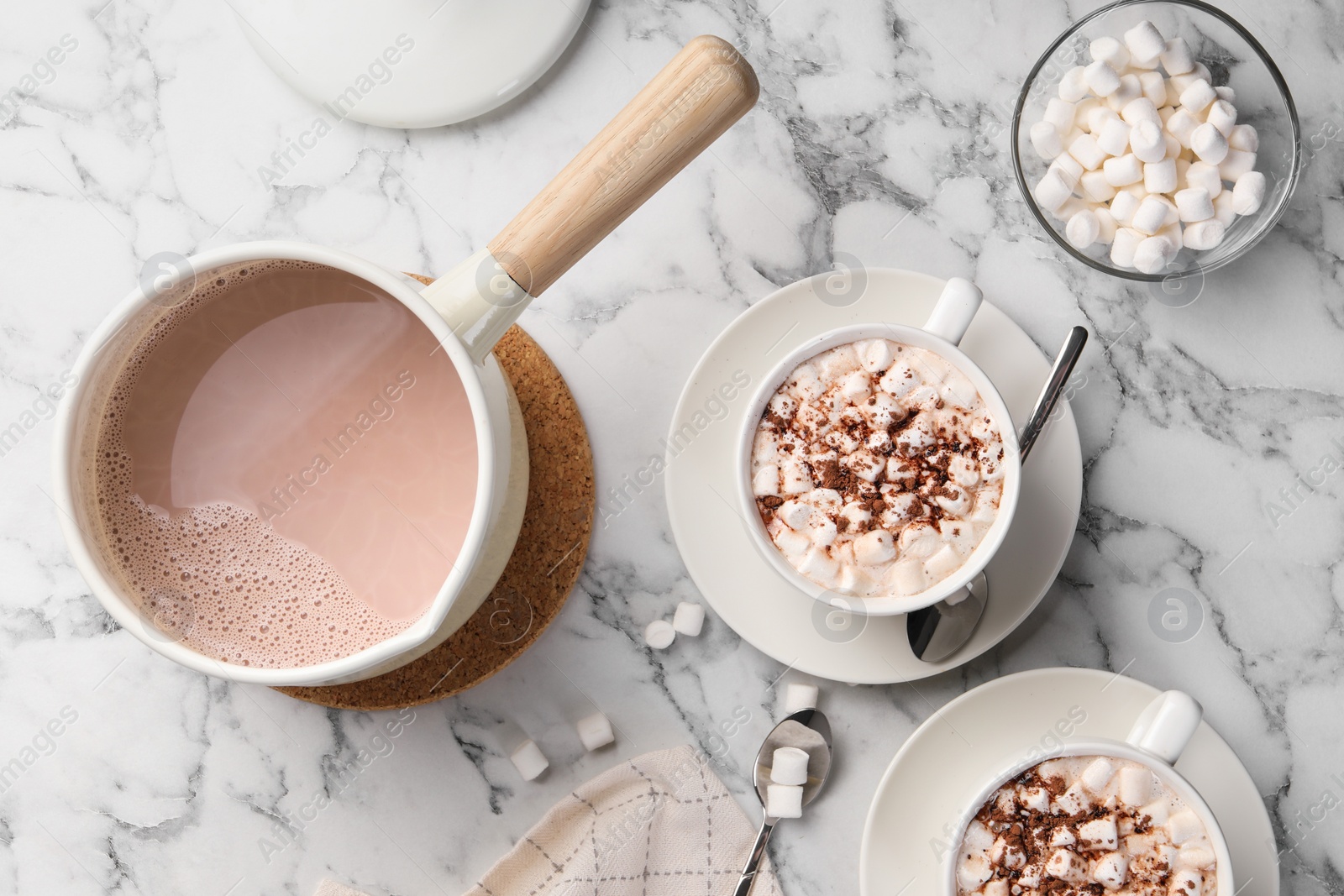 Photo of Aromatic hot chocolate with marshmallows and cocoa powder served on white marble table, flat lay