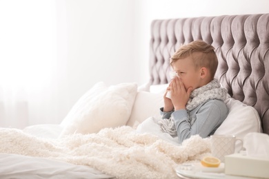 Sick little boy with tissue suffering from cold in bed