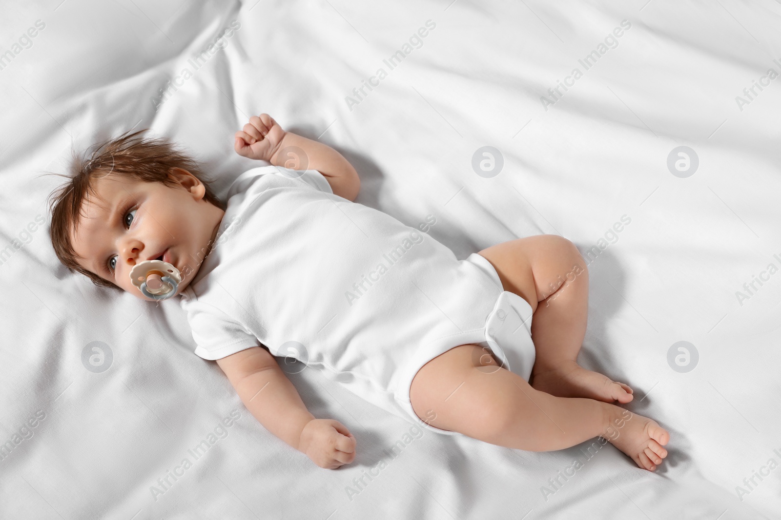 Photo of Cute little baby lying on bed, top view