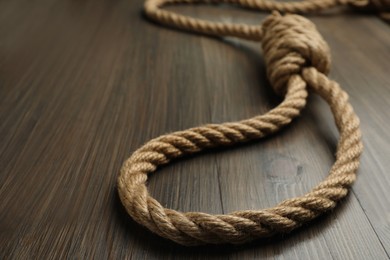 Photo of Rope noose on wooden table, closeup. Space for text