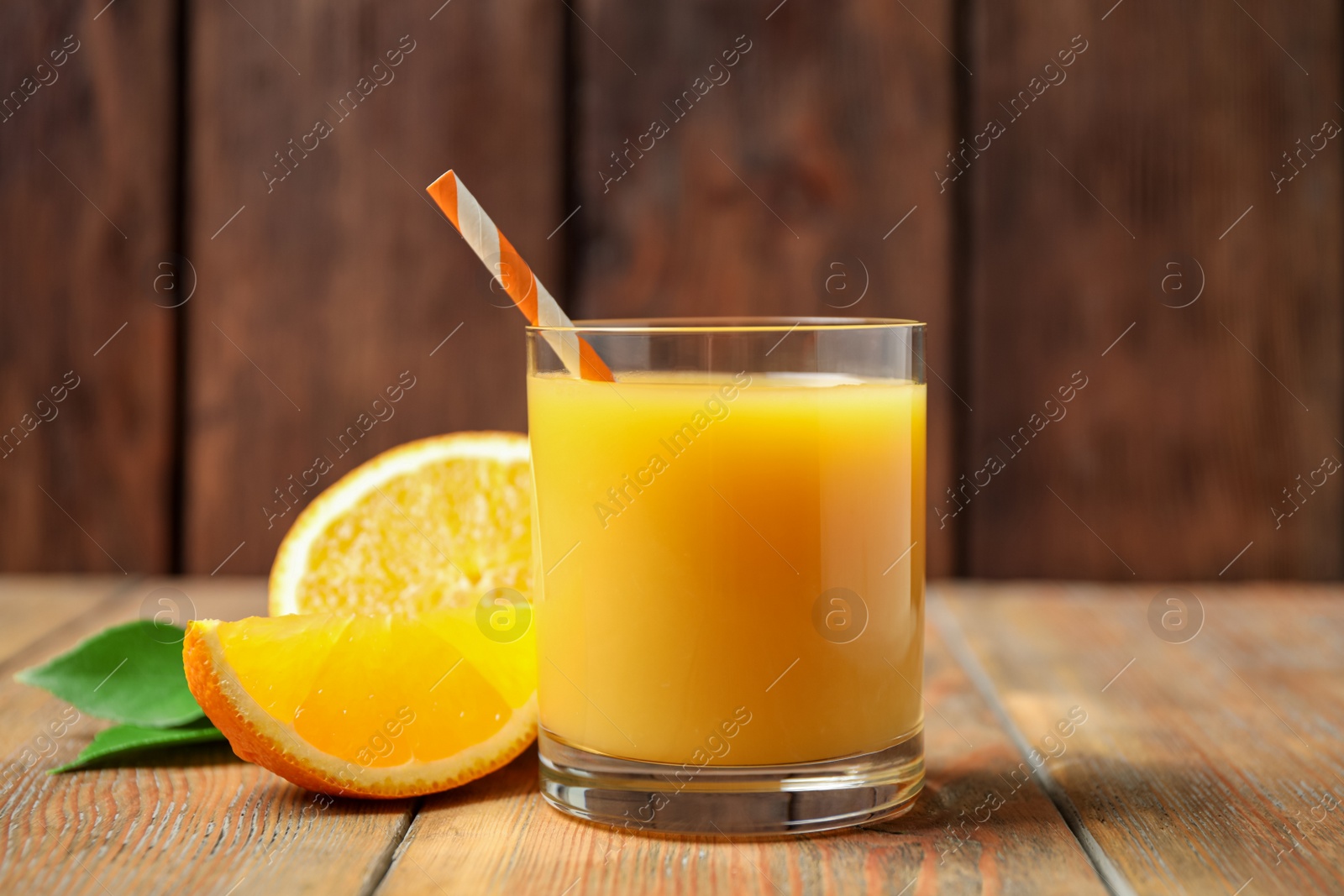 Photo of Glass of orange juice and fresh fruits on wooden table, closeup