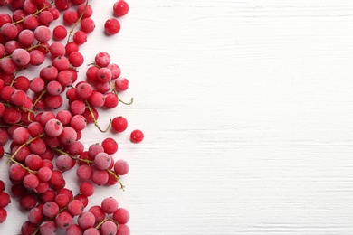 Photo of Tasty frozen red currants on white wooden table, flat lay. Space for text