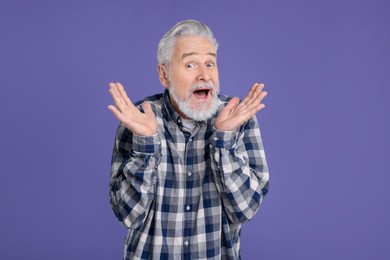 Photo of Portrait of surprised senior man on violet background