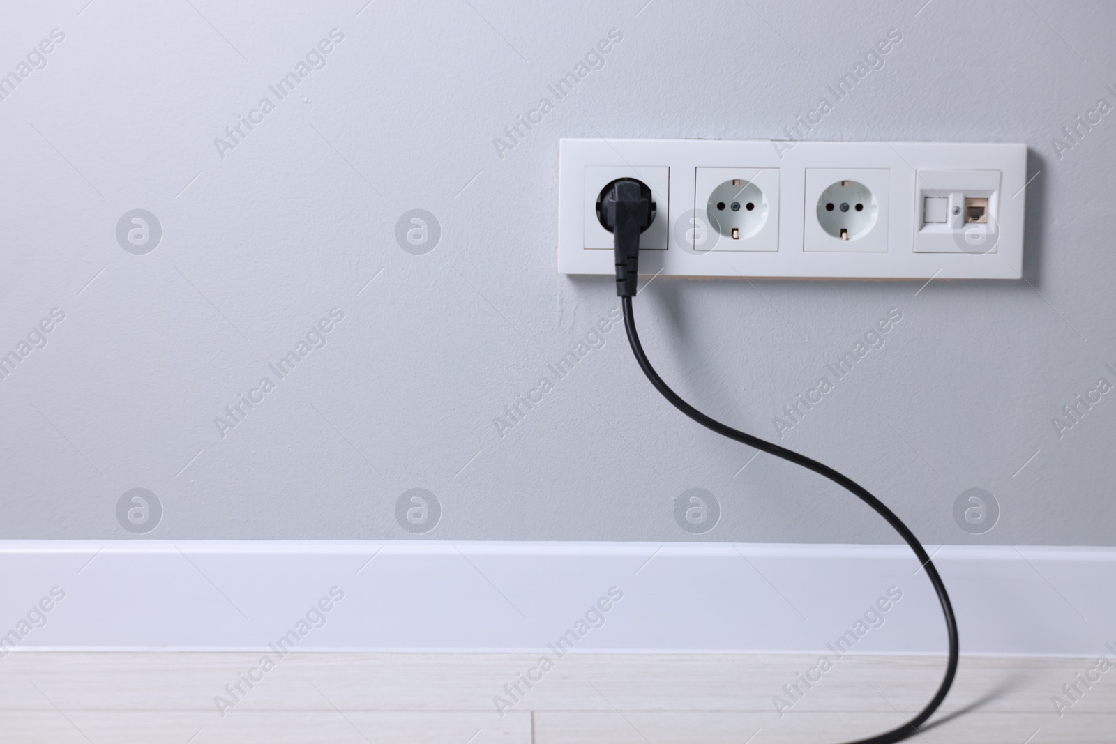 Photo of Power sockets and electric plug on grey wall, space for text