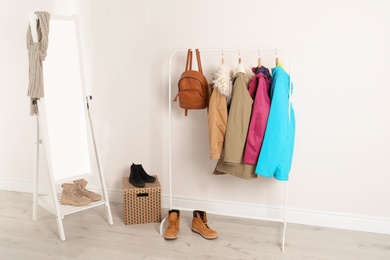 Photo of Modern hallway interior with mirror and clothes on hanger stand