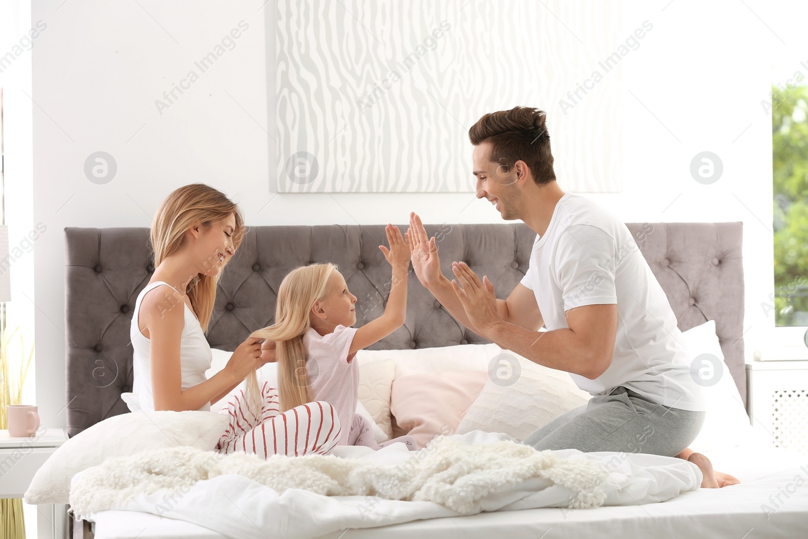 Photo of Happy family having fun on bed with pillows at home. Weekend morning