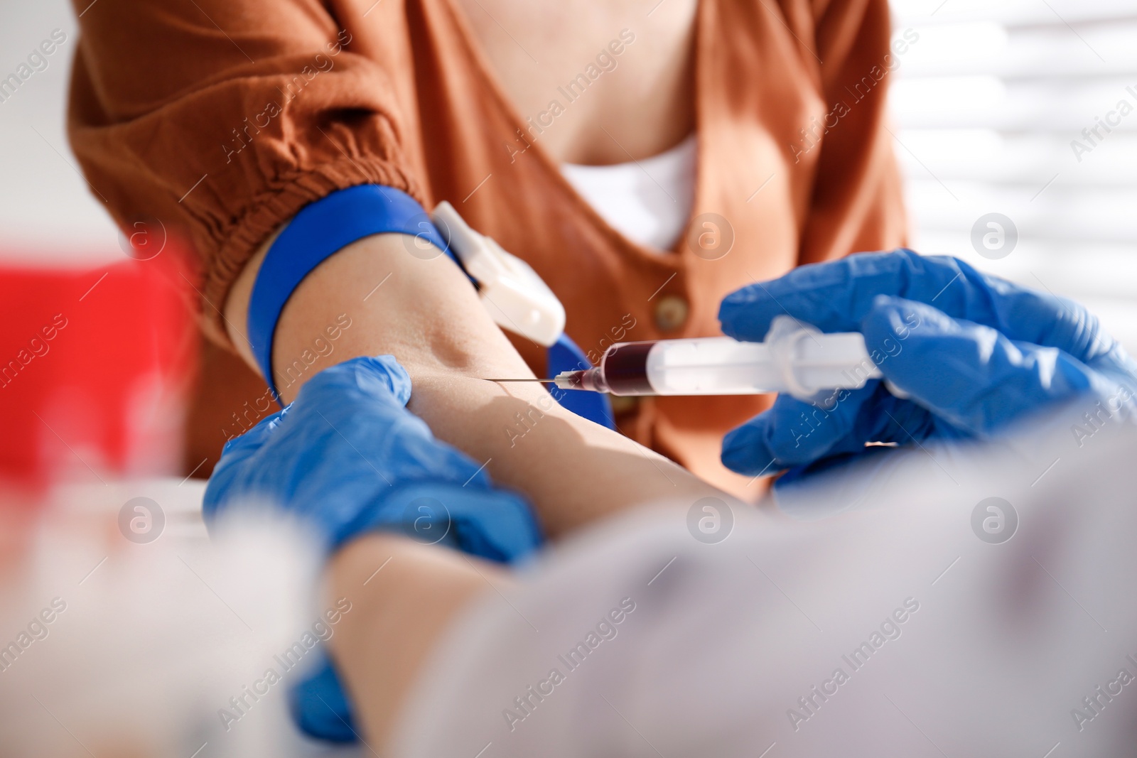 Photo of Nurse drawing blood sample from patient in clinic, closeup