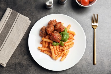 Photo of Delicious pasta with meatballs and tomato sauce on grey background, top view