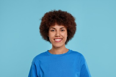 Portrait of happy young woman on light blue background