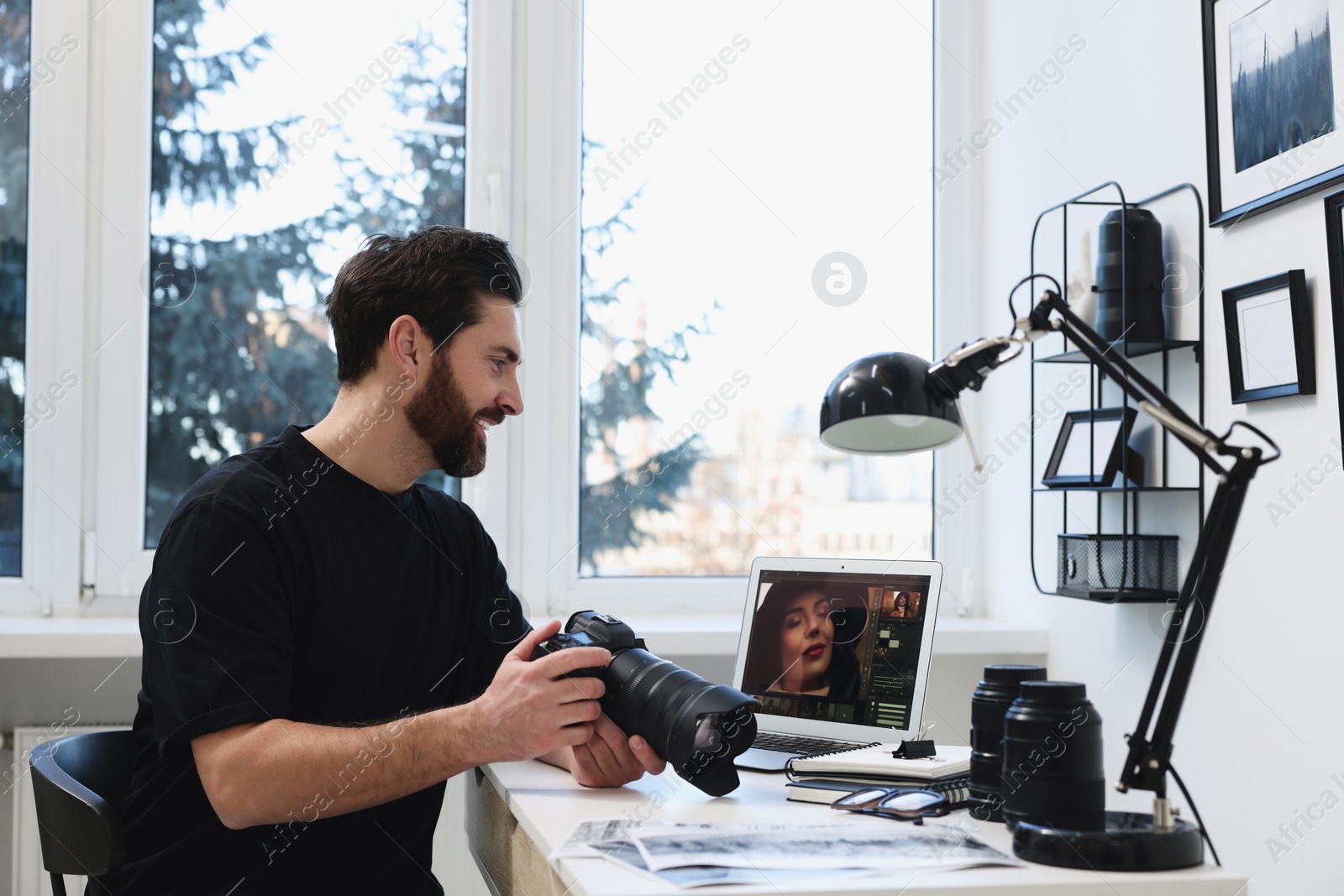 Photo of Professional photographer with digital camera at table in office