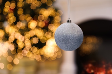 Photo of Beautiful holiday ornament hanging against blurred Christmas lights