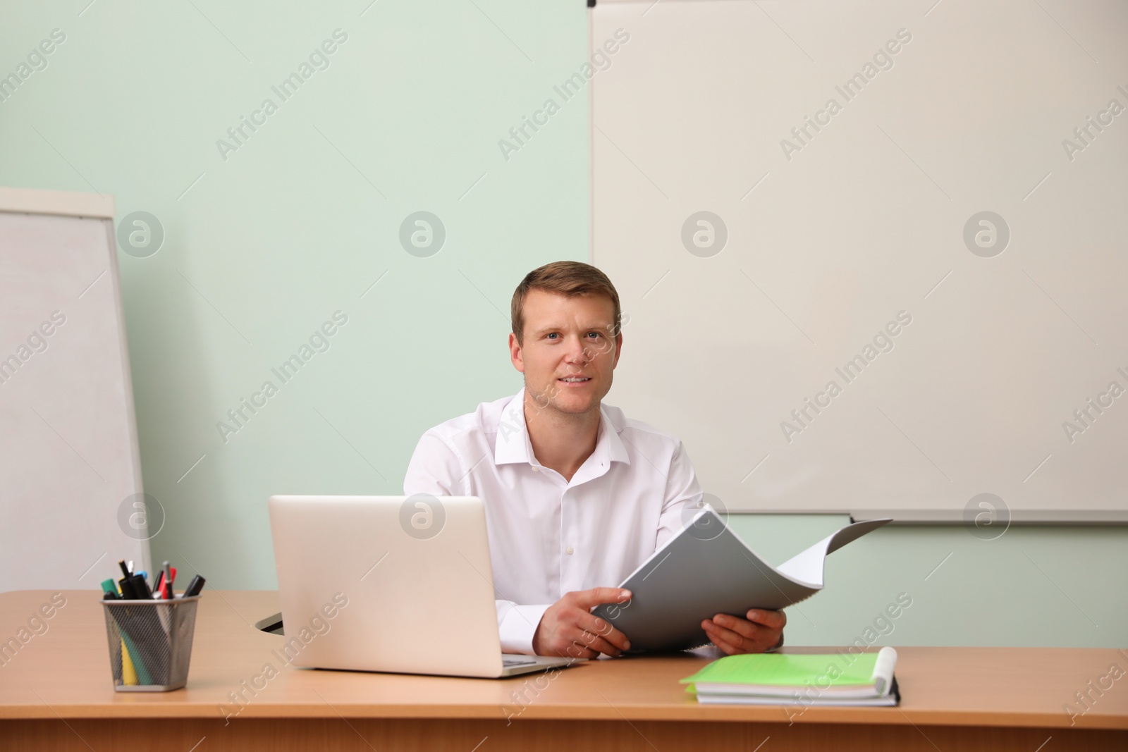 Photo of Male teacher at his desk in classroom