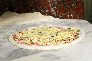 Photo of Raw traditional Italian pizza on table in restaurant kitchen