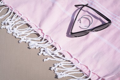 Stylish sunglasses, jewelry and pink blanket on grey surface, above view