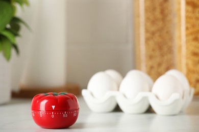 Photo of Kitchen timer in shape of tomato and eggs on white table. Space for text