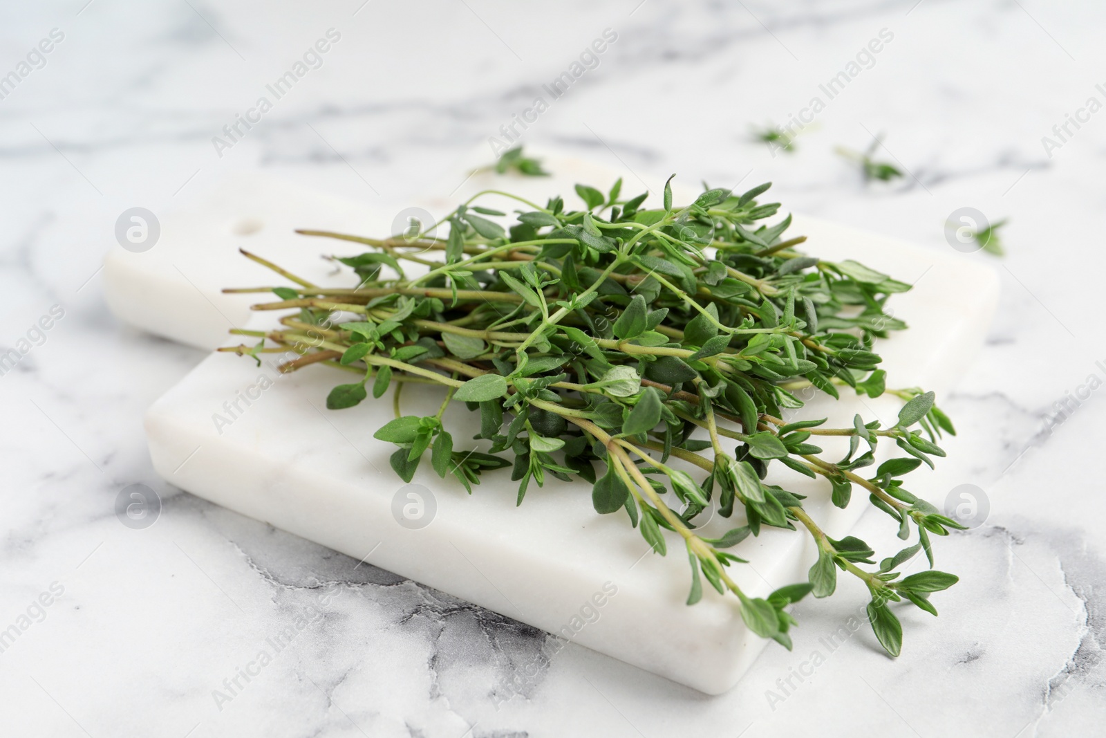 Photo of Bunch of aromatic thyme on white marble table, closeup