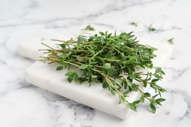 Bunch of aromatic thyme on white marble table, closeup