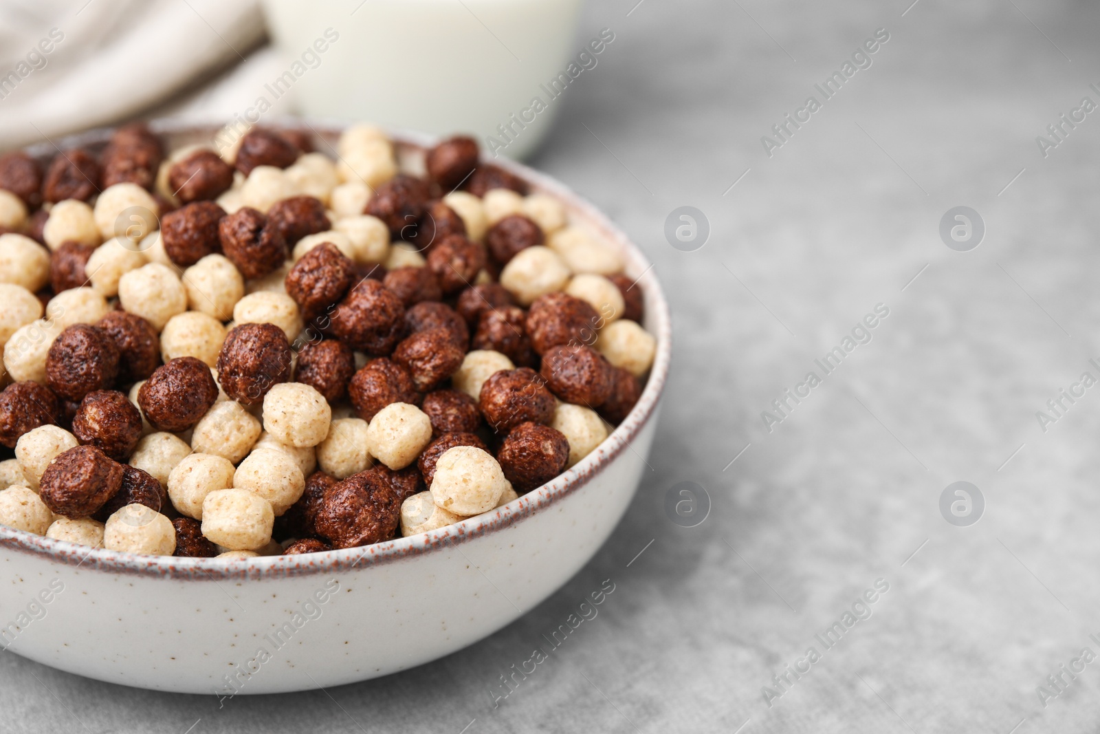 Photo of Tasty cereal balls in bowl on grey table, closeup. Space for text