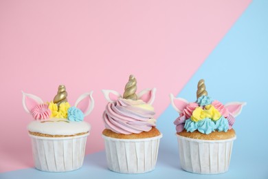 Photo of Three cute sweet unicorn cupcakes on color background