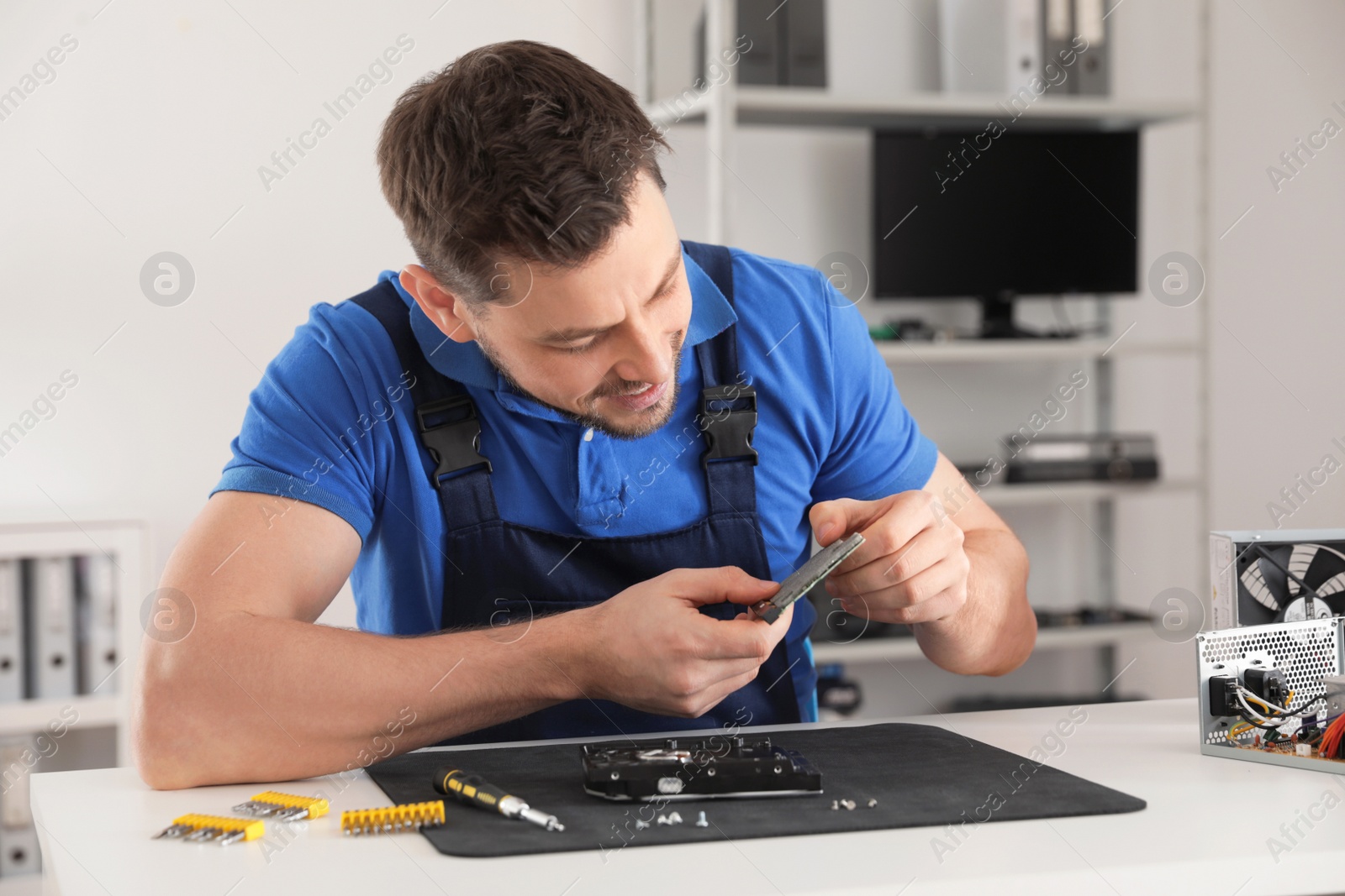 Photo of Male technician repairing hard drive at table indoors