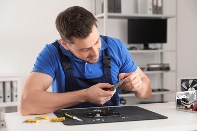 Male technician repairing hard drive at table indoors