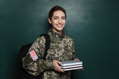 Photo of Female cadet with backpack and books near chalkboard. Military education