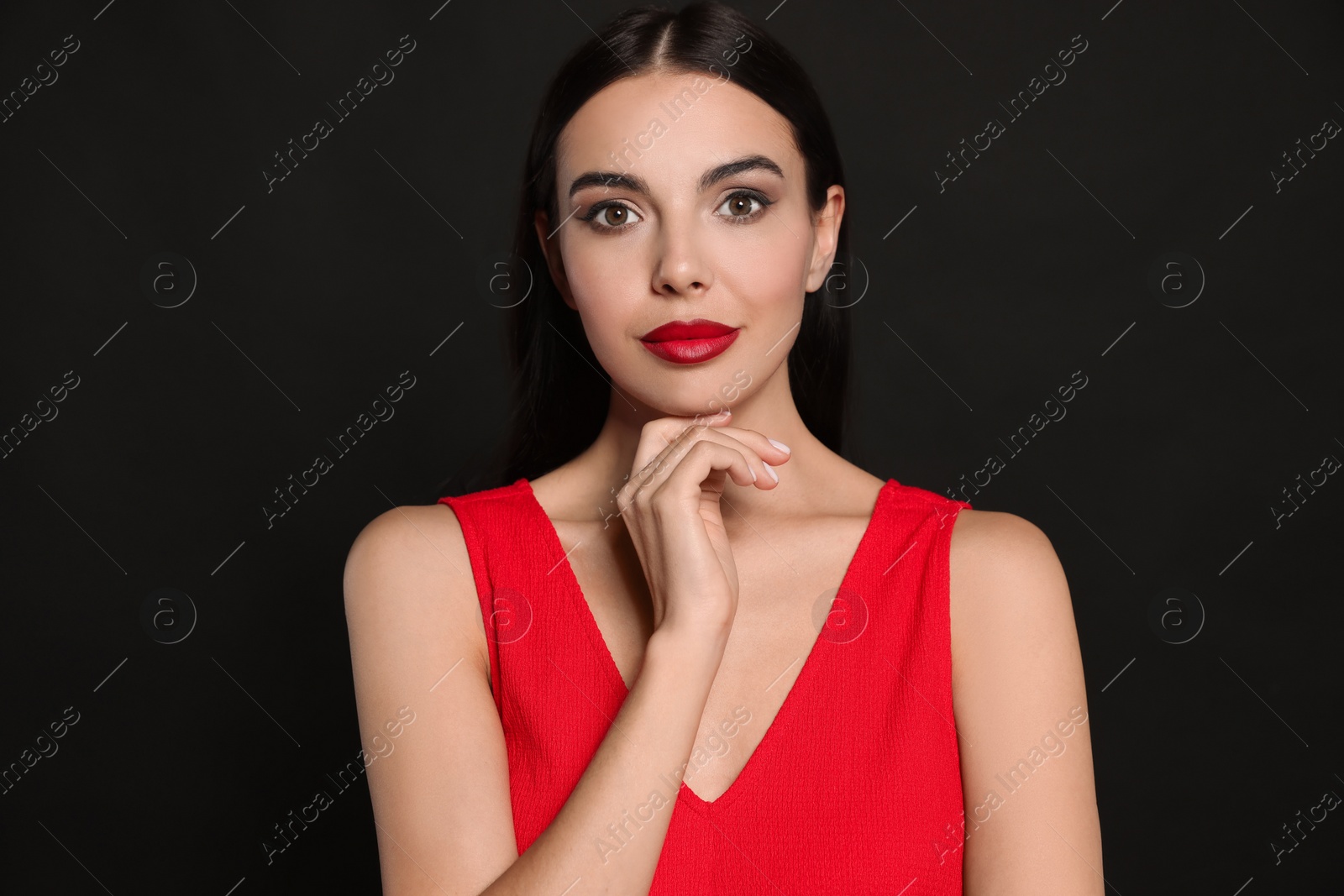 Photo of Portrait of young woman wearing beautiful red lipstick on black background