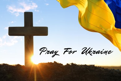 Pray for Ukraine. Phrase, Ukrainian flag waving over cross outdoors at sunrise