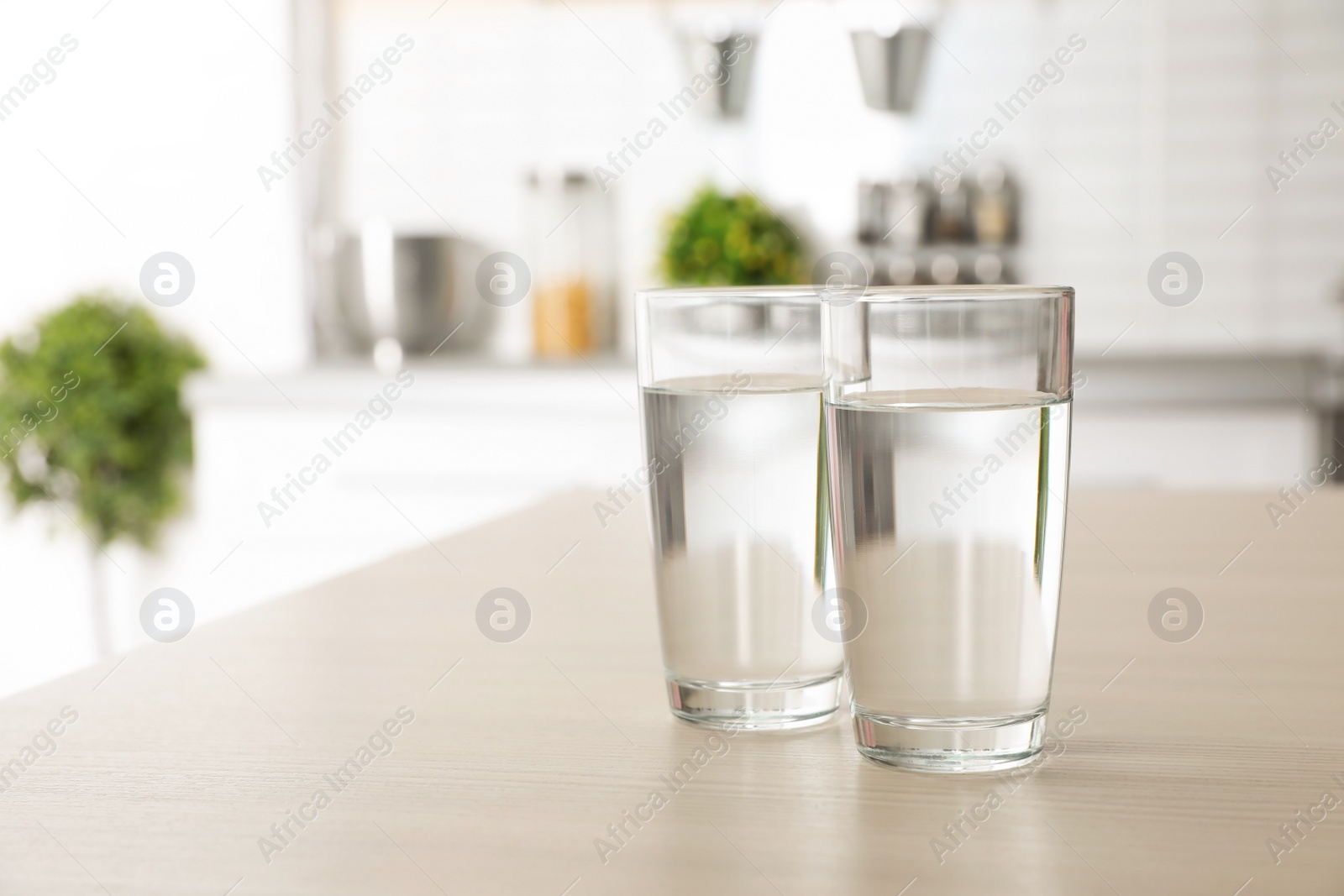 Photo of Glasses of fresh water on table indoors. Space for text