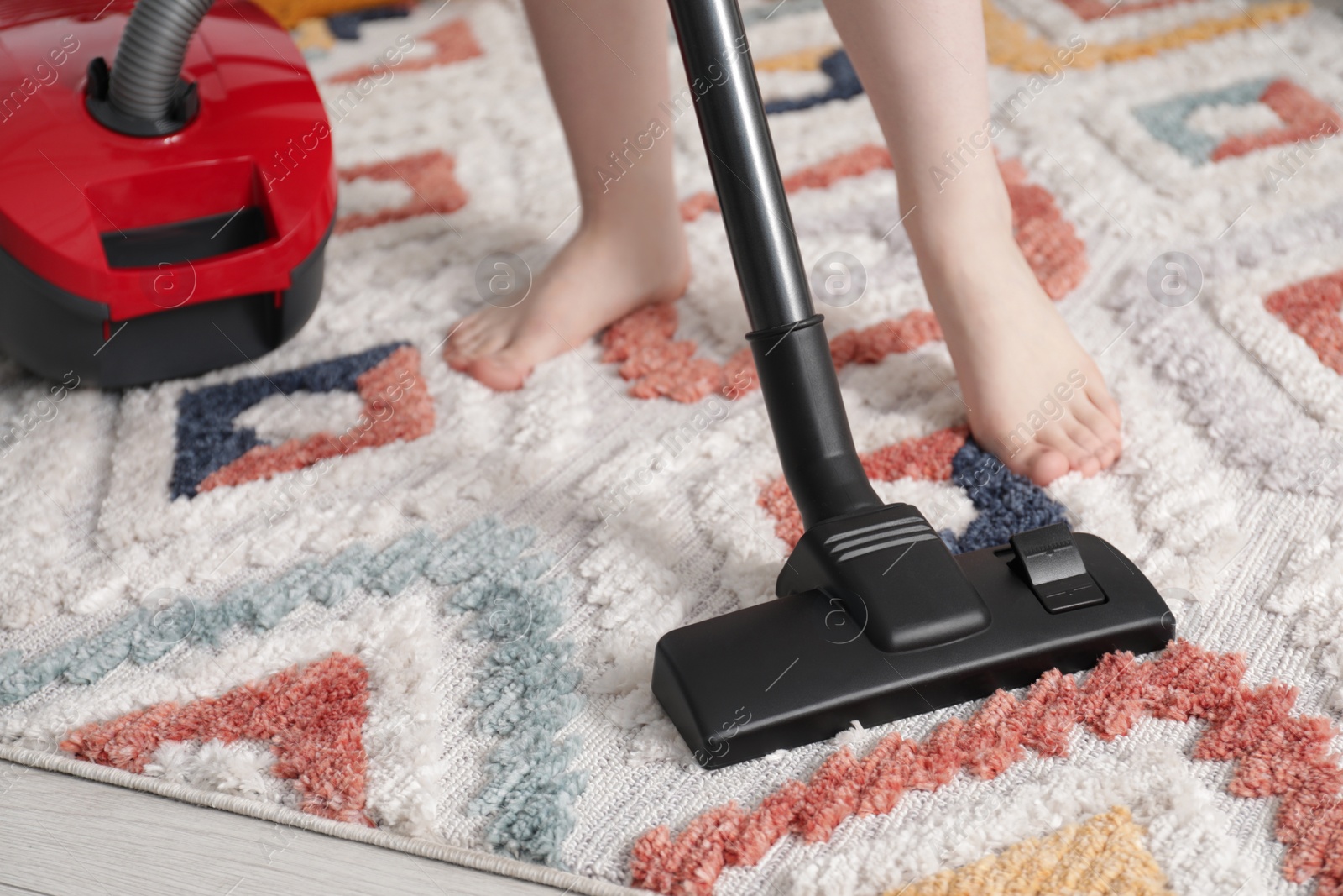 Photo of Woman cleaning carpet with vacuum cleaner at home, closeup