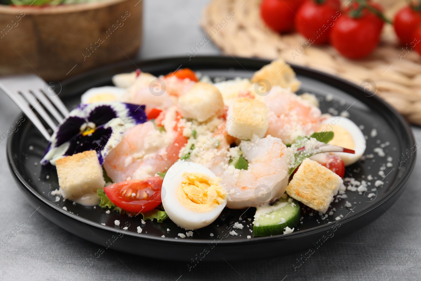 Photo of Delicious Caesar salad with shrimps served on grey table, closeup