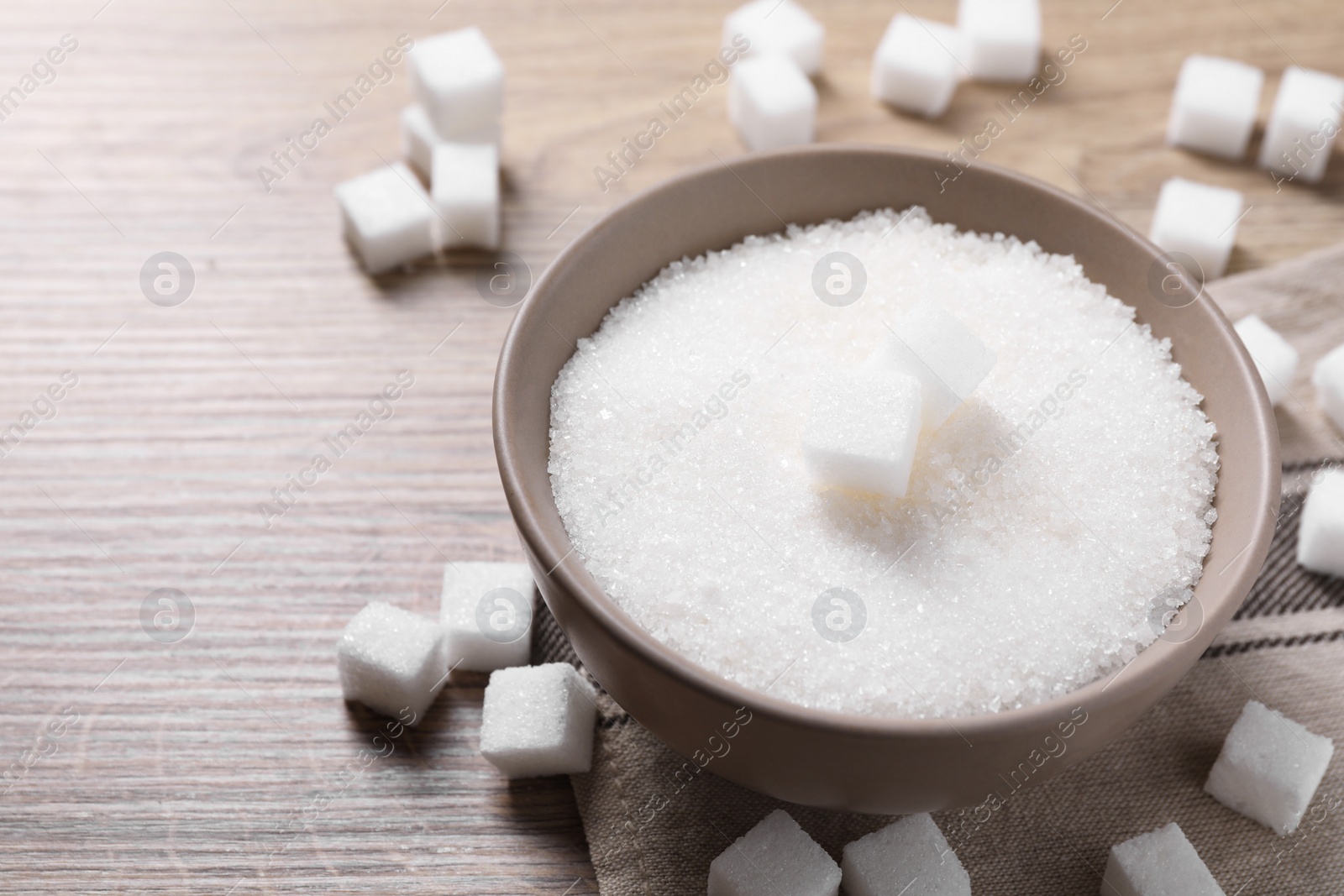 Photo of Different types of white sugar in bowl on wooden table, closeup. Space for text