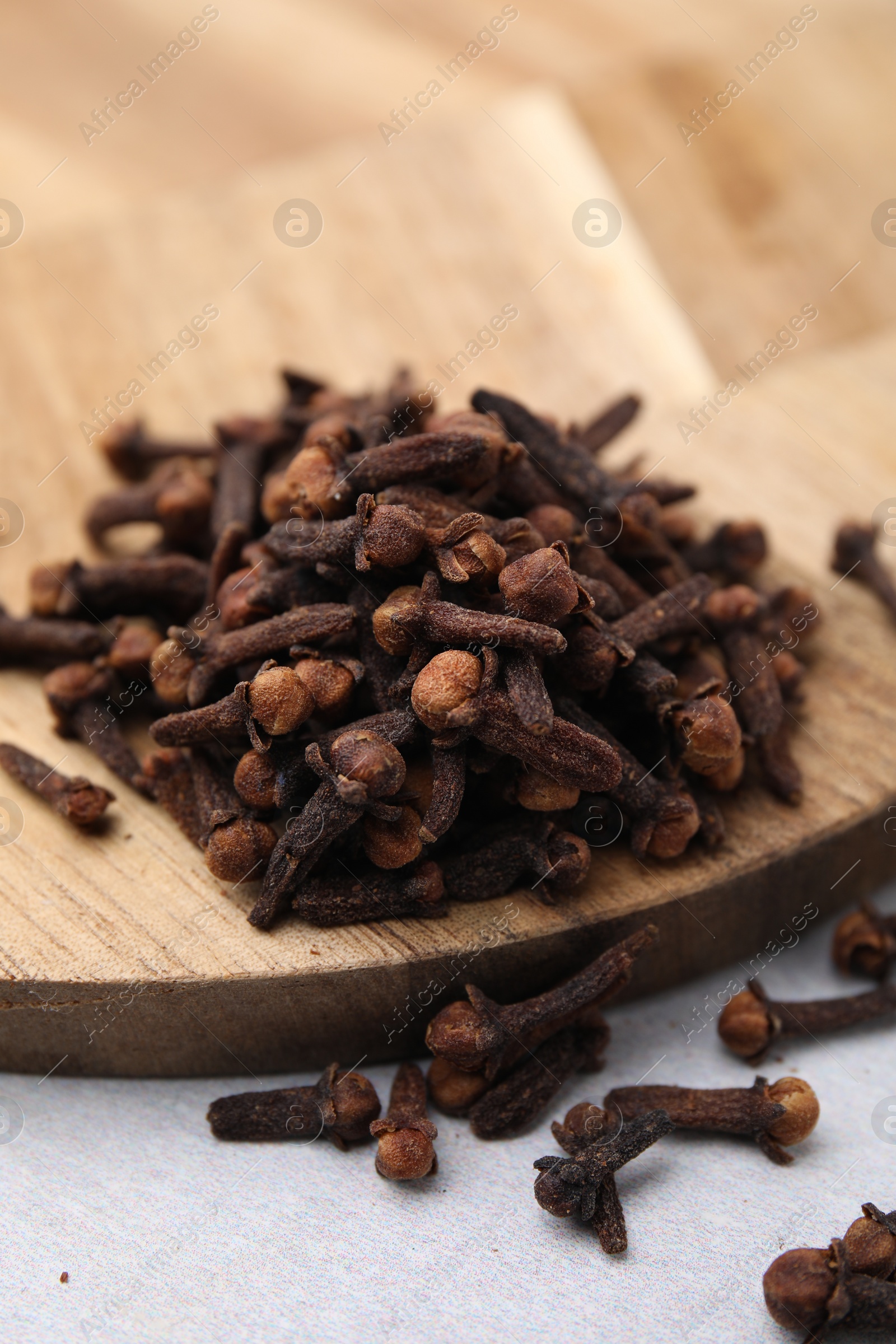 Photo of Pile of aromatic cloves on light table, closeup