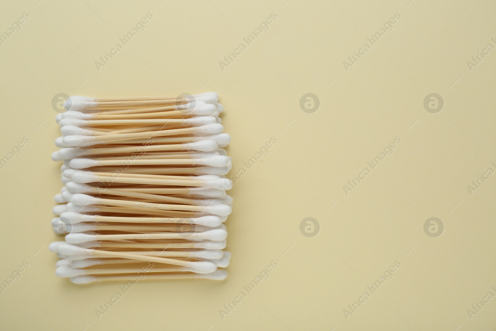 Photo of Many wooden cotton buds on beige background, flat lay. Space for text