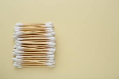 Many wooden cotton buds on beige background, flat lay. Space for text