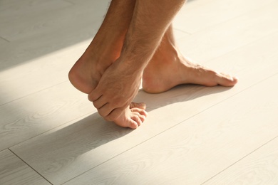 Photo of Man suffering from foot pain indoors, closeup