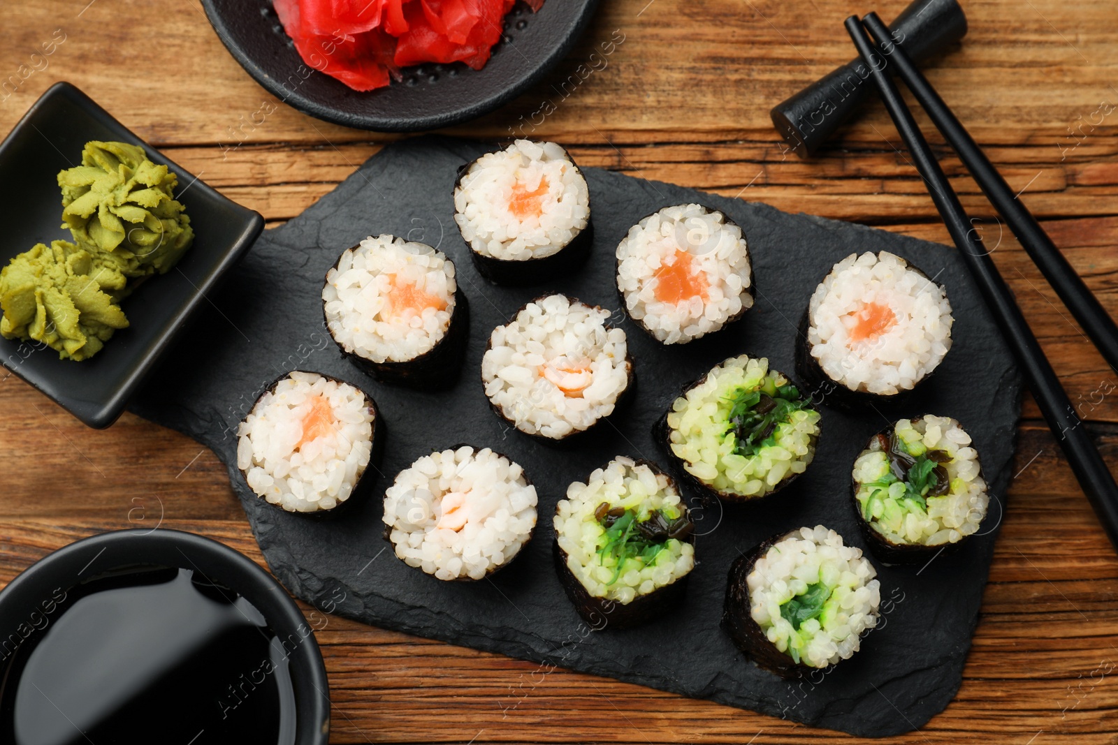 Photo of Tasty sushi rolls served on wooden table, flat lay