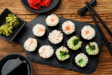 Tasty sushi rolls served on wooden table, flat lay