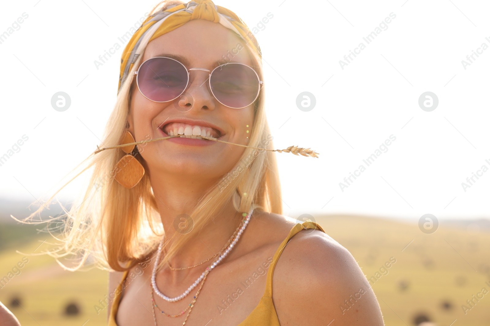 Photo of Beautiful happy hippie woman with spikelet in field, space for text